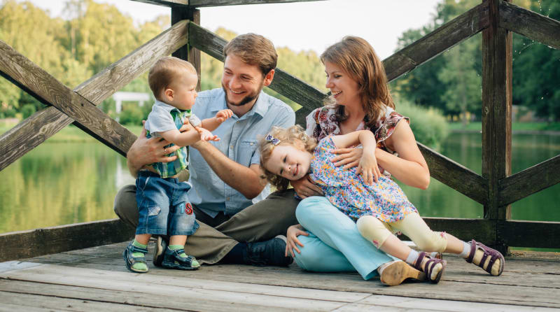 A family plays together on a dock over water.